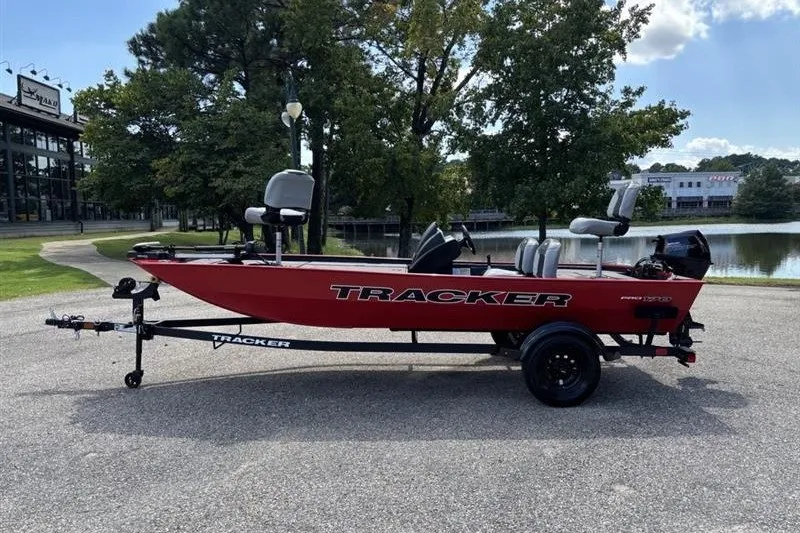 The Image of 2027 Tracker Pro 170 boat on trailer, parked near a lake with trees in background. - 0