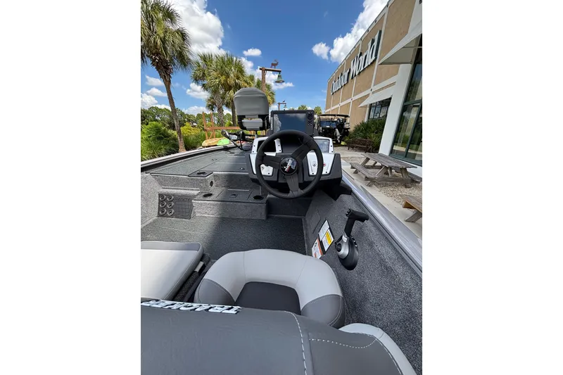 Slide: The Image of 2027 Tracker Pro Team 195 boat interior with steering wheel, parked outside Outdoor World. - 38