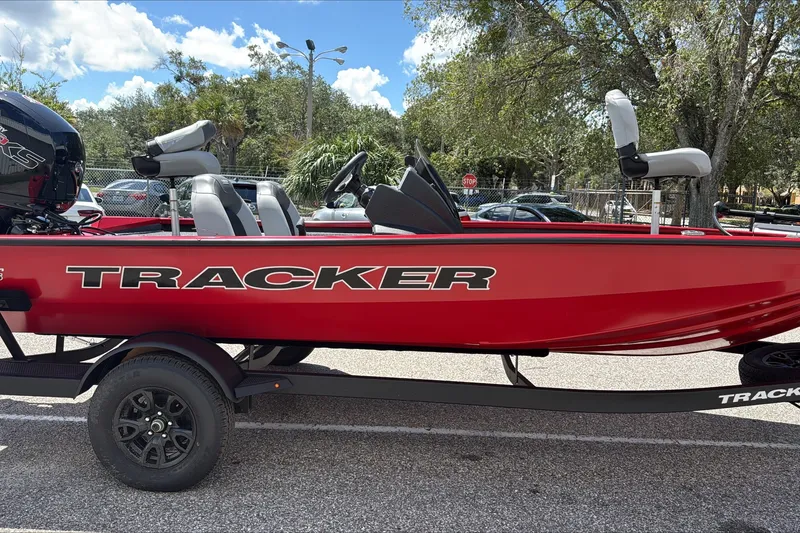 The Image of Red 2027 Tracker Pro Team 195 boat on trailer, parked outdoors under a sunny sky. - 0