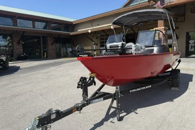 The Image of 2027 Tracker Pro Guide V-16 WT boat on trailer, parked outside a building. - 0