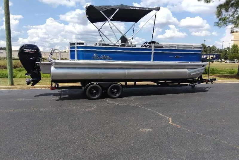 The Image of 2027 Sun Tracker SportFish 22 DLX pontoon boat on trailer, featuring a Mercury outboard motor. - 0