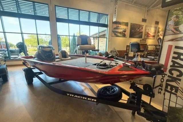 The Image of 2027 Tracker Pro Team 195 boat displayed in showroom, featuring sleek red design and modern amenities. - 0