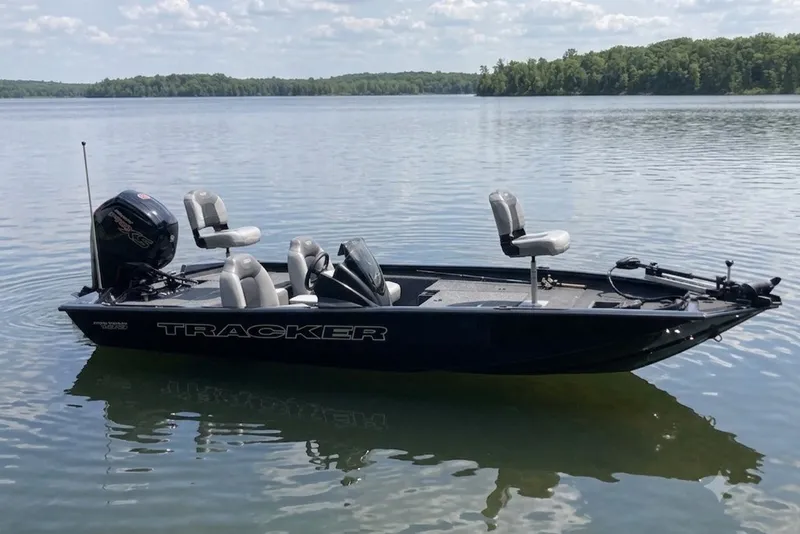 The Image of 2027 Tracker Pro Team 190 boat on a calm lake with scenic forest backdrop. - 1