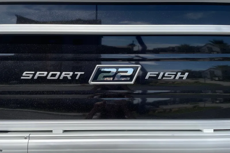 Slide: The Image of 2027 Sun Tracker SportFish 22 DLX logo on a sleek black surface. - 25