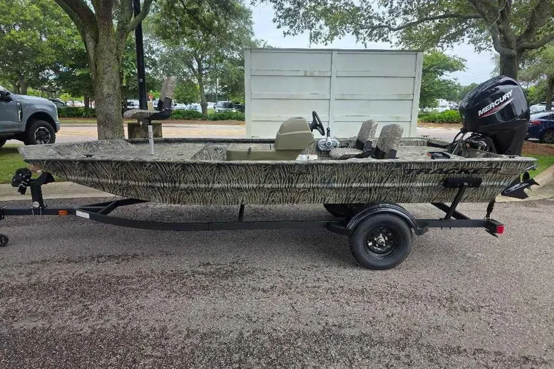 The Image of 2027 Tracker Grizzly 1754 SC boat on trailer, camo design, parked outdoors. - 0