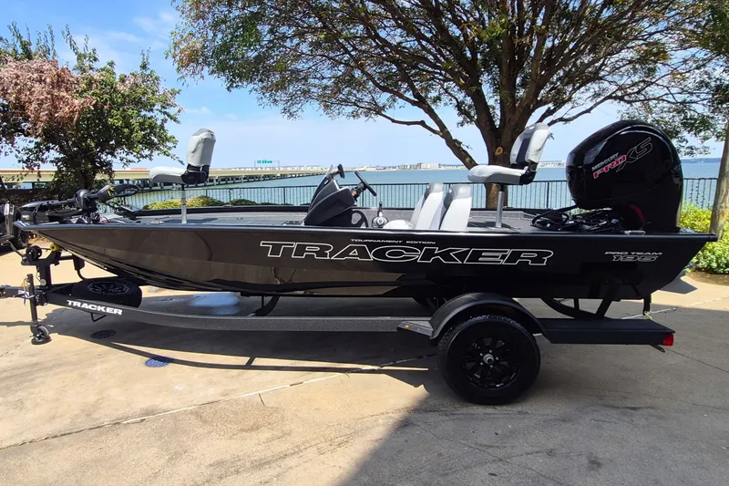 The Image of 2027 Tracker Pro Team 195 boat on trailer by waterfront, under clear sky. - 0