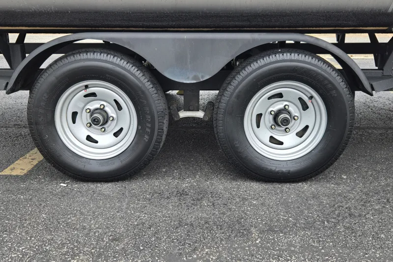 Slide: The Image of Trailer wheels of a 2027 Sun Tracker SportFish 22 DLX on asphalt surface. - 16