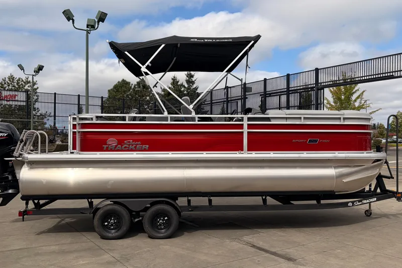The Image of 2027 Sun Tracker SportFish 22 DLX pontoon boat with red exterior and black canopy. - 0