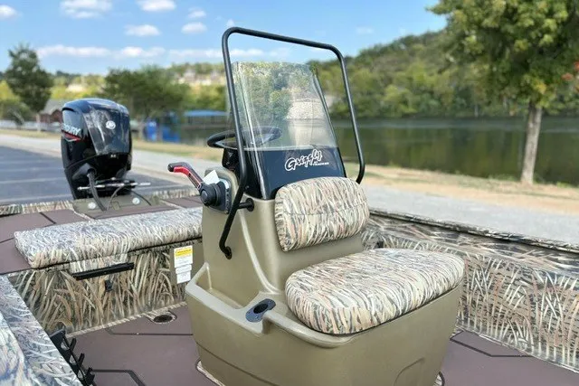 Slide: The Image of 2027 Tracker Grizzly 1860 CC boat with camo seats, near a serene lake. - 19