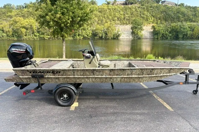 The Image of 2027 Tracker Grizzly 1860 CC boat with Mercury engine, parked by a scenic river. - 0