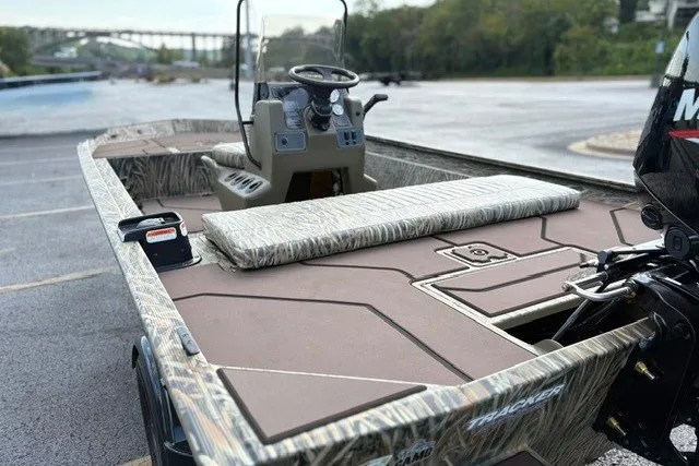 Slide: The Image of 2027 Tracker Grizzly 1860 CC boat with camo design, parked on a paved surface. - 15