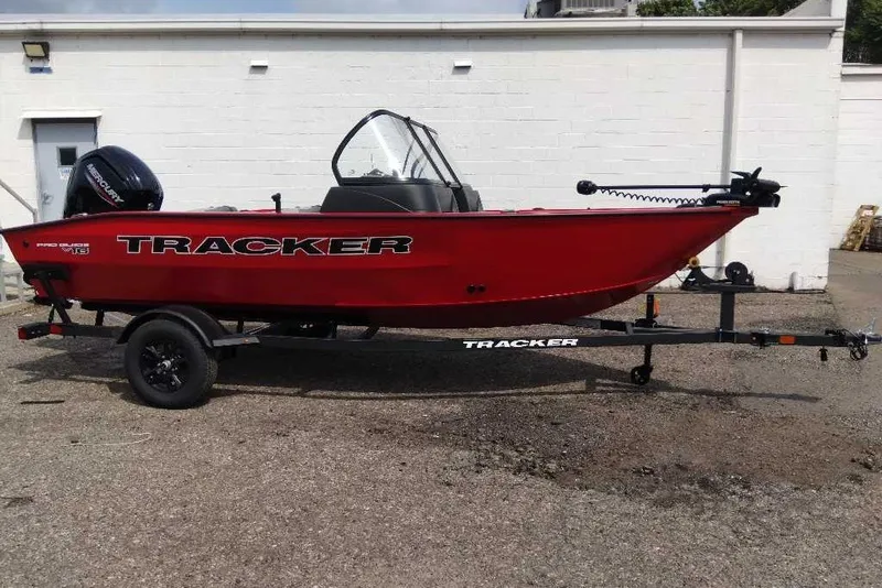 The Image of Red 2027 Tracker Pro Guide V-16 WT boat on trailer, parked outdoors. - 0