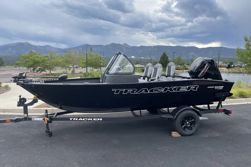 The Image of 2027 Tracker Pro Guide V-16 WT boat on trailer, parked with scenic mountain backdrop. - 0