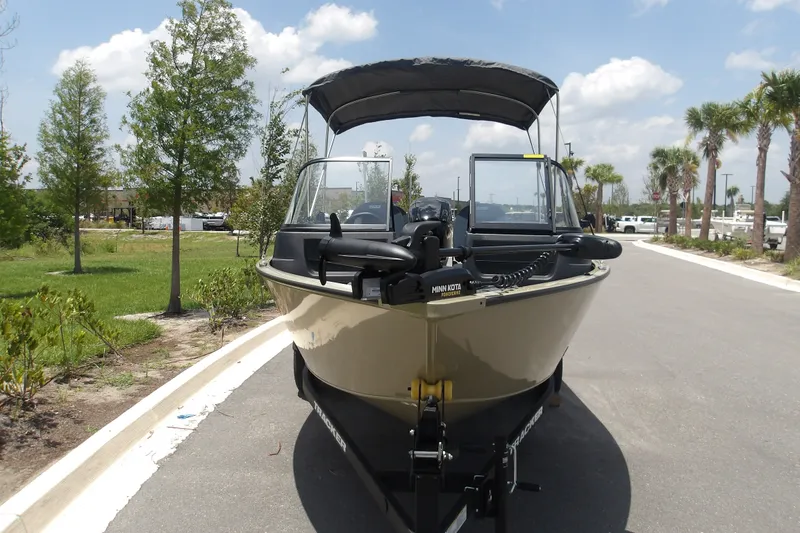 Slide: The Image of 2027 Tracker Pro Guide V-16 WT boat on trailer, parked outdoors under sunny sky. - 14