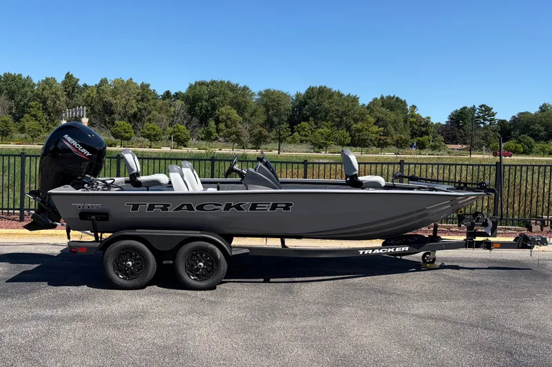 The Image of 2027 Tracker Pro Team 195 boat on trailer, parked outdoors with trees in background. - 0