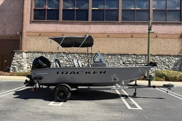 The Image of 2027 Tracker Pro Guide V-16 WT boat parked outdoors with canopy and trailer. - 0