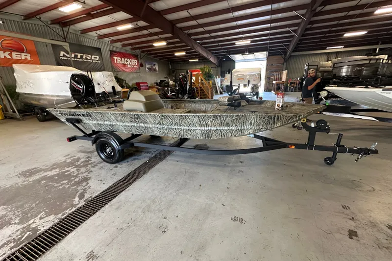 The Image of 2027 Tracker Grizzly 1754 SC boat in showroom, camo design, on trailer. - 0