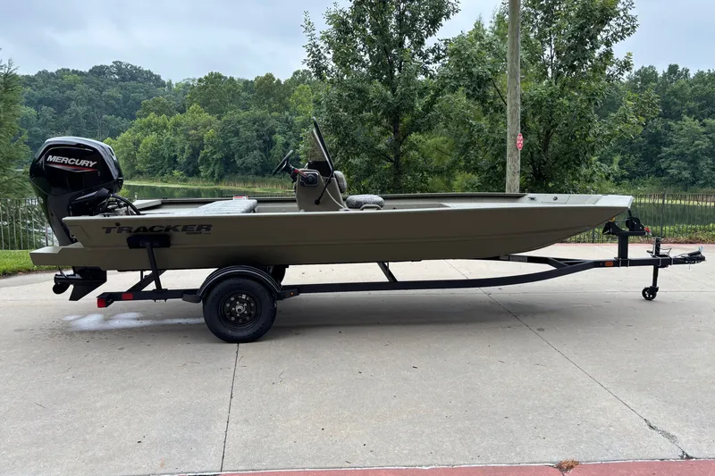 The Image of 2027 Tracker Grizzly 1860 CC boat on trailer, parked outdoors near lush greenery. - 0