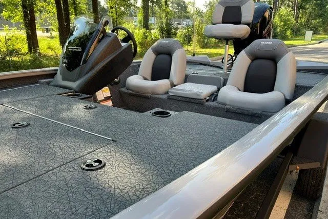 Slide: The Image of 2027 Tracker Pro Team 195 boat interior with seating and steering console in a wooded area. - 14