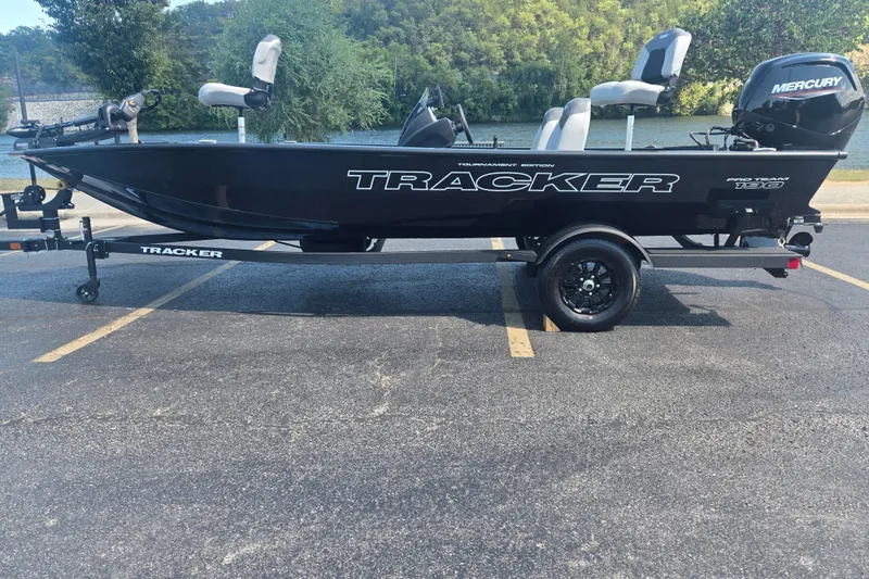 The Image of 2027 Tracker Pro Team 190 boat on trailer, parked near a scenic lake. - 0