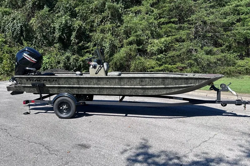 The Image of 2027 Tracker Grizzly 1860 CC boat on trailer, parked outdoors with trees in background. - 0