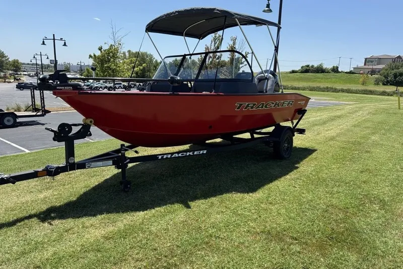 Slide: The Image of 2027 Tracker Pro Guide V-16 WT boat on trailer, parked on grass under clear sky. - 13