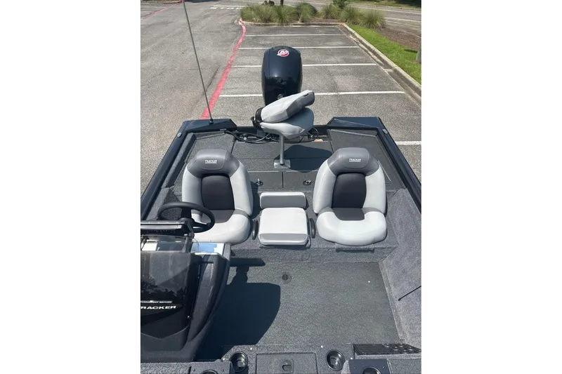 Slide: The Image of 2027 Tracker Pro Team 195 boat interior with seating and steering wheel in a parking lot. - 13