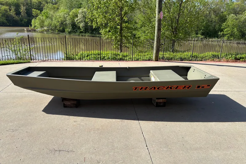 The Image of 2027 Tracker Grizzly 12 Jon boat on concrete near a scenic lake. - 0