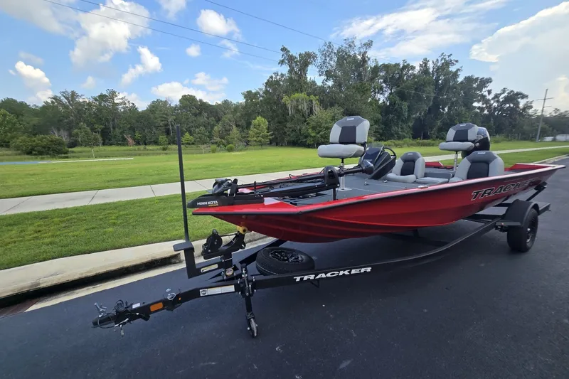 Slide: The Image of 2027 Tracker Pro Team 195 boat on trailer, parked on a paved road with grassy background. - 28