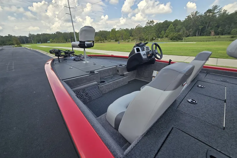 Slide: The Image of 2027 Tracker Pro Team 195 boat interior with steering console and seating, parked on a paved road. - 30