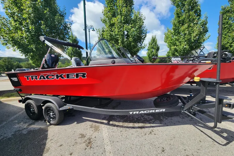 The Image of Red 2027 Tracker Targa V-18 Combo boat on trailer, parked outdoors under blue sky. - 0