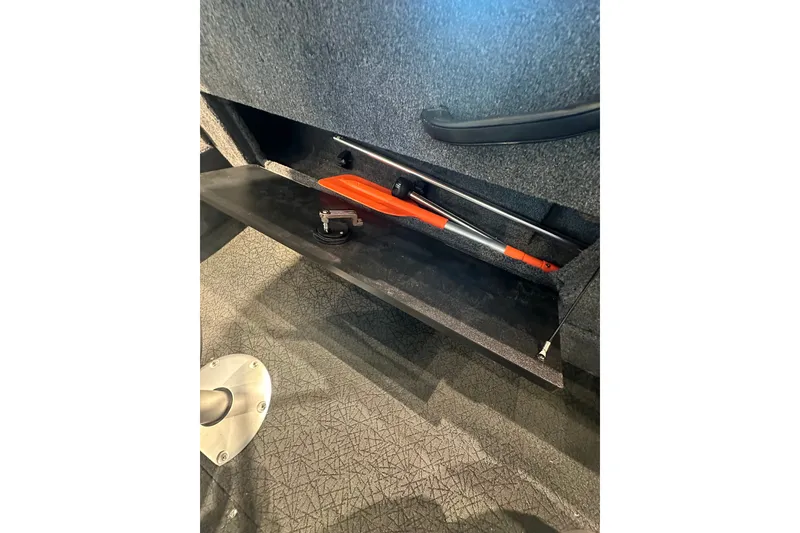 Slide: The Image of Storage compartment in 2027 Tracker Targa V-18 Combo boat, featuring a secured orange tool. - 31