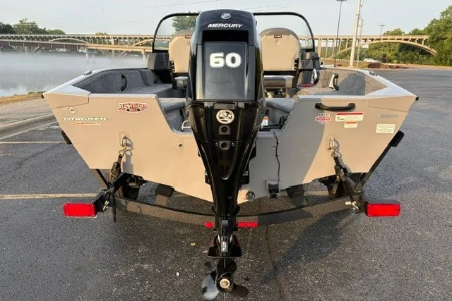 Slide: The Image of 2027 Tracker Pro Guide V-16 WT boat with Mercury 60 engine, parked near a river. - 13