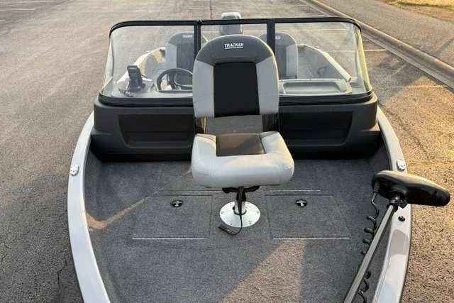 Slide: The Image of 2027 Tracker Pro Guide V-16 WT boat with seating and windshield, parked on pavement. - 25