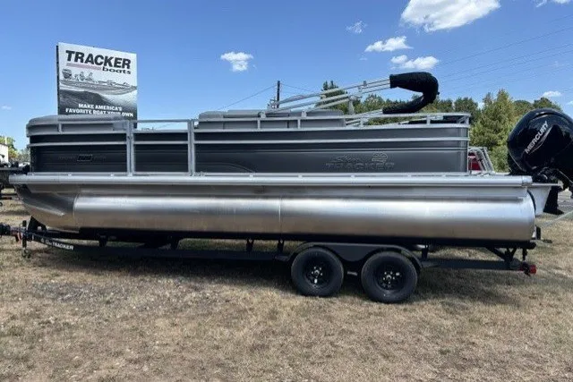 The Image of 2027 Sun Tracker SportFish 22 DLX pontoon boat on trailer, displayed outdoors. - 0