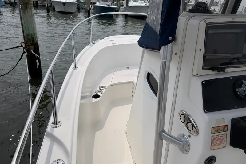 Slide: The Image of 2002 Boston Whaler 210 Outrage boat interior at dock, featuring console and seating area. - 16