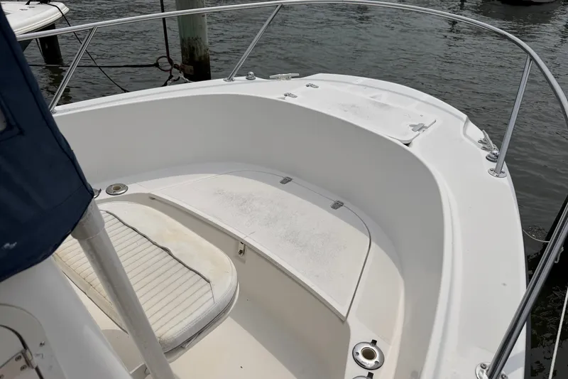 Slide: The Image of 2002 Boston Whaler 210 Outrage boat interior with seating and railing, docked by water. - 19