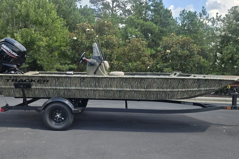 The Image of 2027 Tracker Grizzly 1860 CC boat on trailer, camo design, parked outdoors. - 0