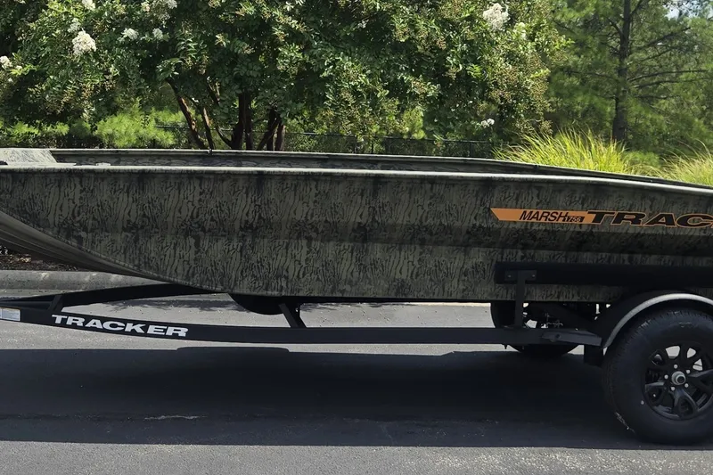 Slide: The Image of 2027 Tracker Grizzly 1860 CC boat on trailer, camo design, parked outdoors. - 65