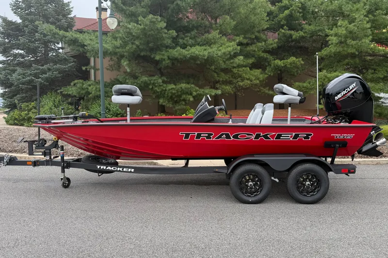The Image of Red 2027 Tracker Pro Team 195 boat on trailer, parked on road with trees in background. - 0
