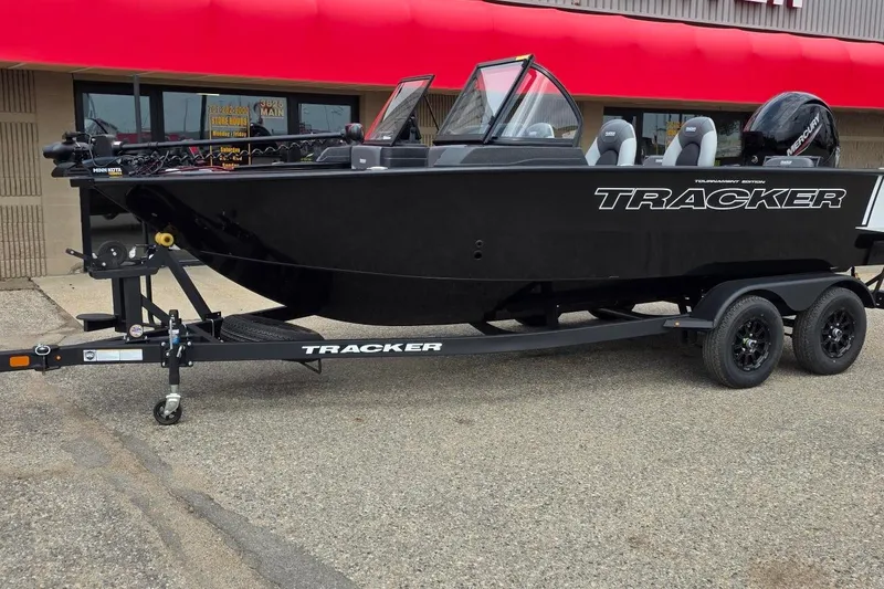 Slide: The Image of 2027 Tracker Targa V-18 Combo boat on trailer, parked outside a building with red awning. - 38