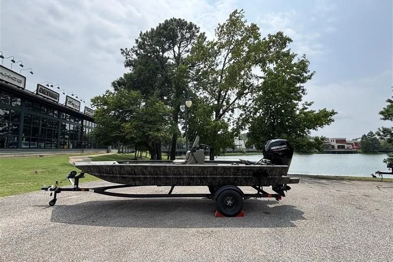 The Image of 2027 Tracker Grizzly 1860 CC boat on trailer near a lake and trees. - 0