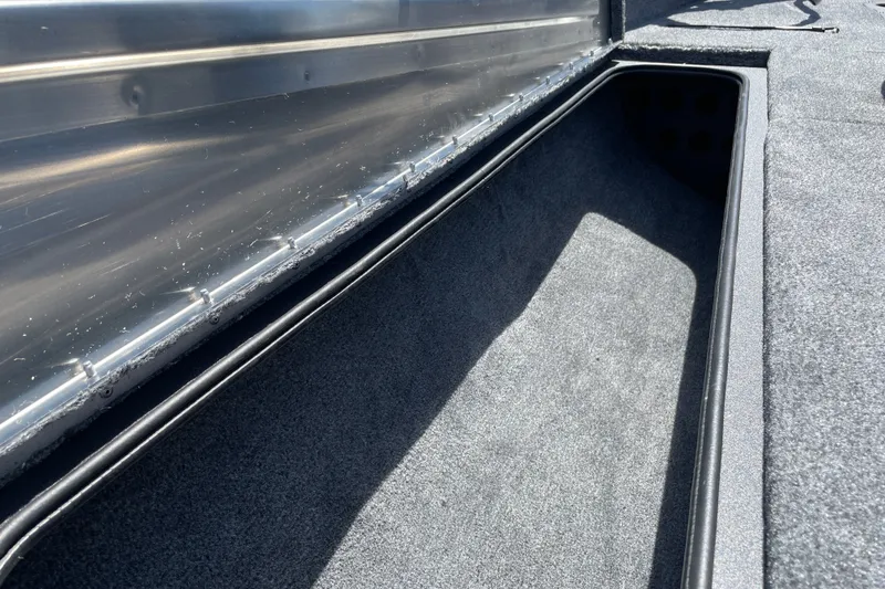 Slide: The Image of Storage compartment of 2027 Tracker Pro Team 190 boat, featuring carpeted interior and metal trim. - 20