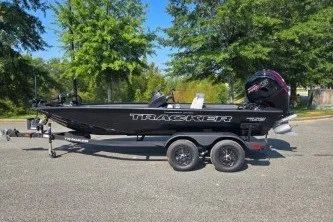 The Image of 2027 Tracker Pro Team 195 boat on trailer, parked outdoors with trees in background. - 0