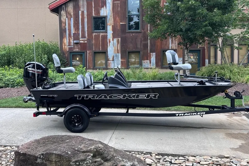The Image of 2027 Tracker Pro 170 boat on trailer, parked outdoors near rustic building. - 0