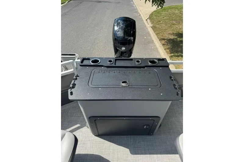 Slide: The Image of 2027 Sun Tracker SportFish 22 DLX boat console with motor, featuring cup holders and storage. - 16