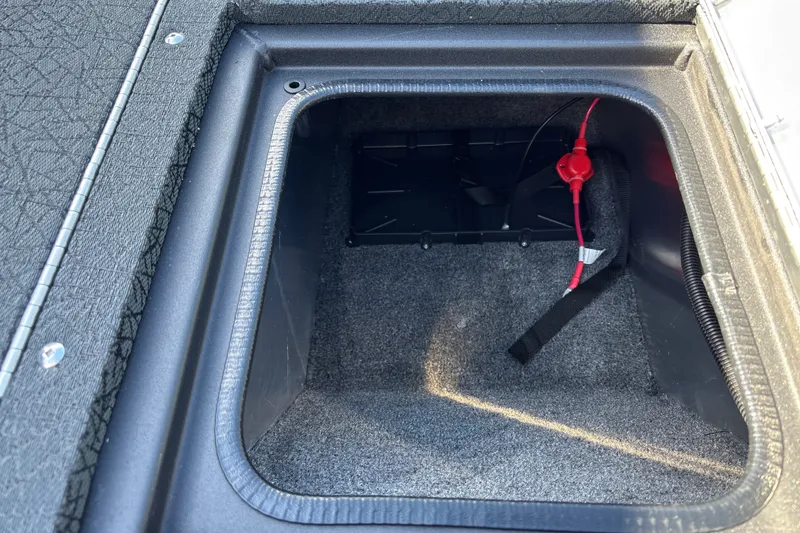 Slide: The Image of Storage compartment of 2027 Tracker Pro Guide V-16 WT boat, featuring carpeted interior and wiring. - 26