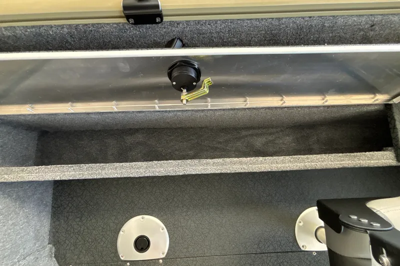 Slide: The Image of 2027 Tracker Pro Guide V-16 WT boat interior storage compartment with secure latch and carpeted finish. - 32