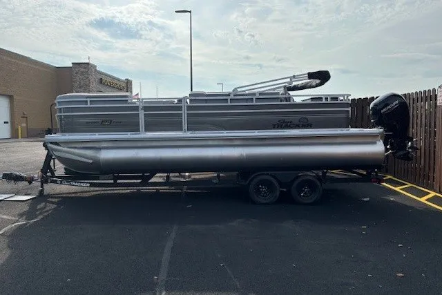 The Image of 2027 Sun Tracker SportFish 22 DLX pontoon boat on trailer in parking lot. - 0