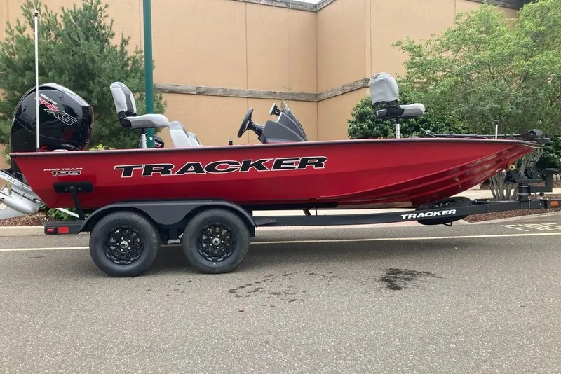 The Image of 2027 Tracker Pro Team 195 boat on trailer, red exterior, parked outdoors. - 0